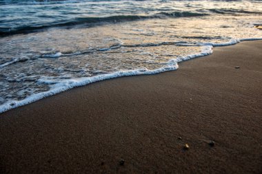 Günbatımı sırasında kumsala yaklaşırken dalgalar