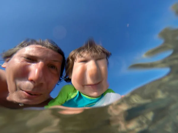 Underwater view of a father and her daughter with distorted face — Stock Photo, Image