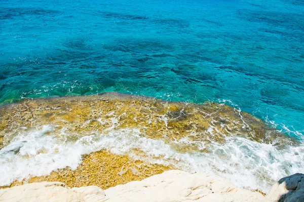 クリスタルクリアターコイズブルーの海の水の背景と岩の海岸 — ストック写真