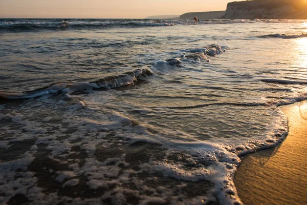 Fale zbliża się do piaszczystej plaży podczas zachodu słońca — Zdjęcie stockowe