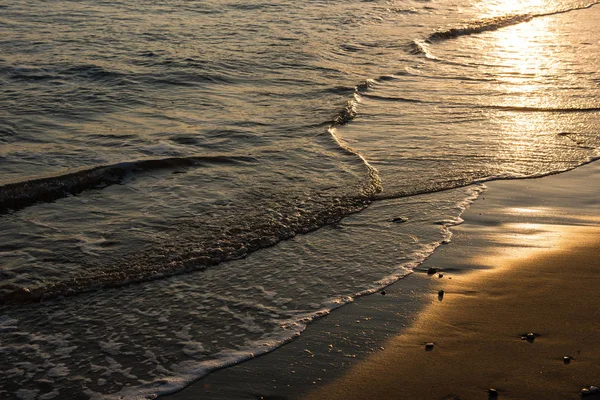 Vlny se blíží písečná pláž při západu slunce — Stock fotografie
