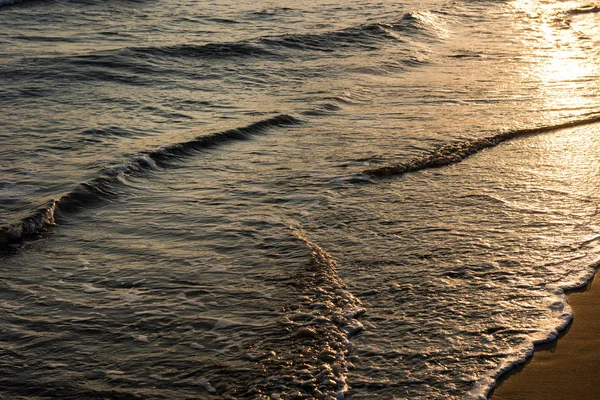 Onde che si avvicinano alla spiaggia sabbiosa durante il tramonto — Foto Stock