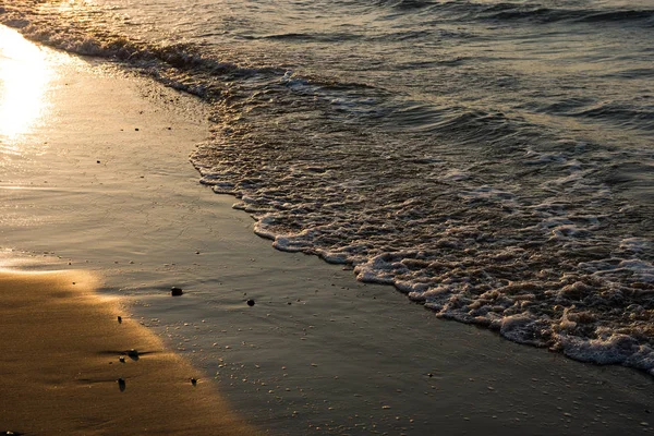 Onde che si avvicinano alla spiaggia sabbiosa durante il tramonto — Foto Stock