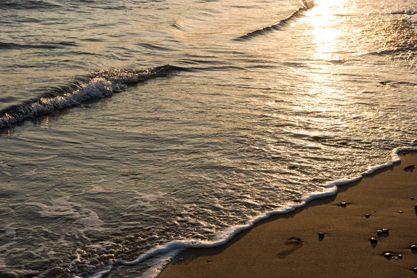 Vlny se blíží písečná pláž při západu slunce — Stock fotografie