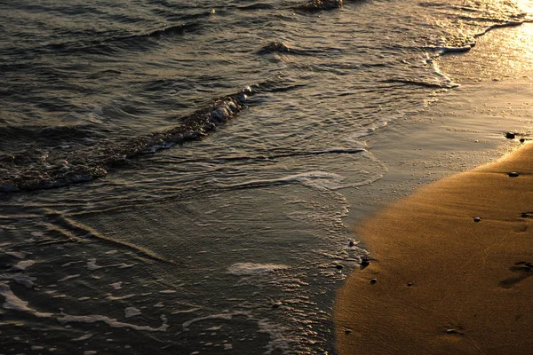 Vlny se blíží písečná pláž při západu slunce — Stock fotografie