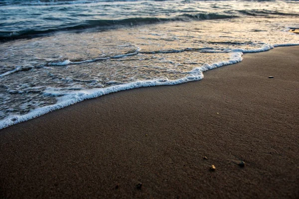 Vagues approchant la plage de sable au coucher du soleil — Photo