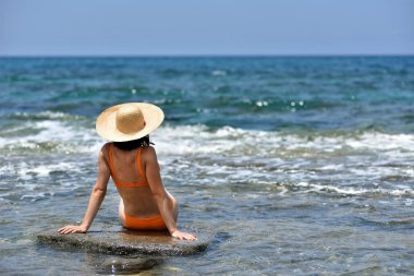 Seksi bikini bronzlaşma kadın rahatlatıcı bir şapka ile sahilde