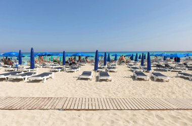Turist beach umbrel altında bir kumlu plajda şezlong üzerinde rahatlatıcı