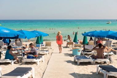 Turist beach umbrel altında bir kumlu plajda şezlong üzerinde rahatlatıcı