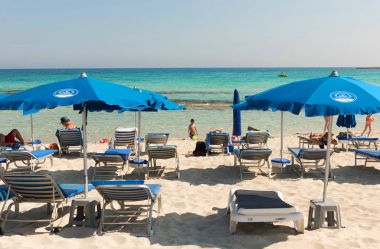 Turist beach umbrel altında bir kumlu plajda şezlong üzerinde rahatlatıcı