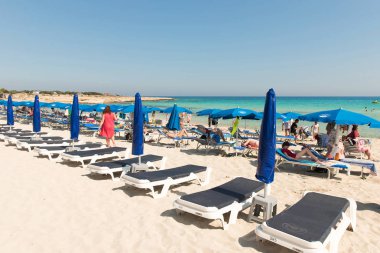 Turist beach umbrel altında bir kumlu plajda şezlong üzerinde rahatlatıcı