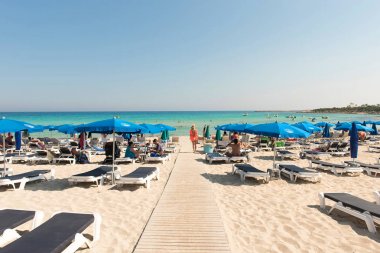 Turist beach umbrel altında bir kumlu plajda şezlong üzerinde rahatlatıcı