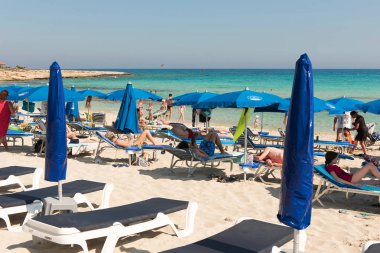 Turist beach umbrel altında bir kumlu plajda şezlong üzerinde rahatlatıcı