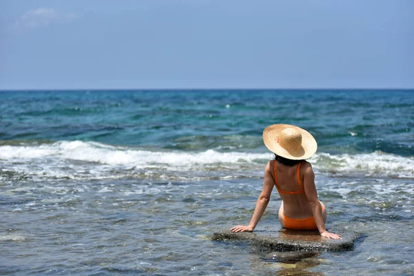 Sexy mujer bronceadora bikini relajante en la playa con un sombrero —  Fotos de Stock