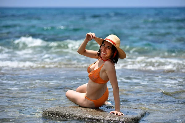 Sexy mujer bronceadora bikini relajante en la playa con un sombrero — Foto de Stock