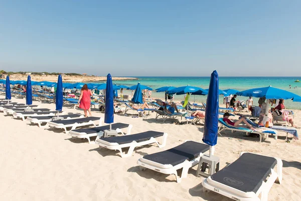 Туристы отдыхают на шезлонгах на песчаном пляже под пляжем umbrel — стоковое фото