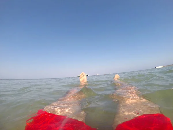 穿着红色泳衣的游泳者的腿漂浮在海里 — 图库照片