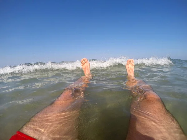 Ноги пловца в красных купальниках, плавающих в море — стоковое фото