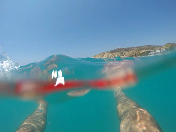 Pernas de um nadador de fato de banho vermelho a flutuar no mar — Fotografia de Stock