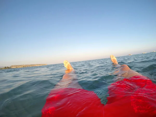 Pernas de um nadador de fato de banho vermelho a flutuar no mar — Fotografia de Stock