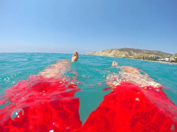 Benen van een zwemmer in rode badmode drijvend in de zee — Stockfoto