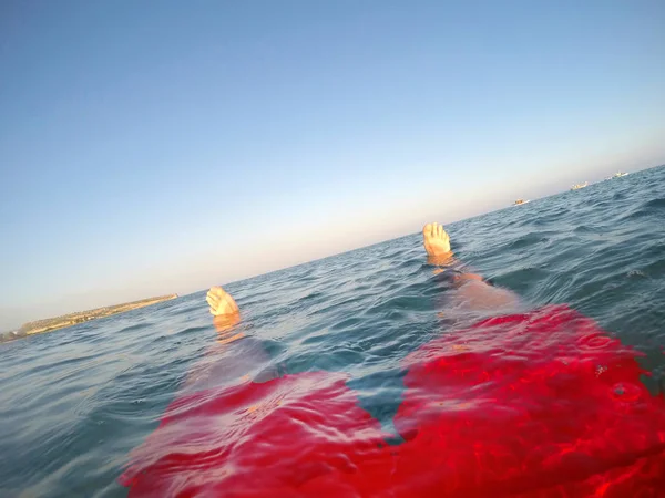 Benen av en simmare i röda badbyxor flytande i havet — Stockfoto