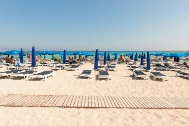 Turist beach umbrel altında bir kumlu plajda şezlong üzerinde rahatlatıcı