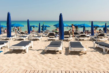 Turist beach umbrel altında bir kumlu plajda şezlong üzerinde rahatlatıcı