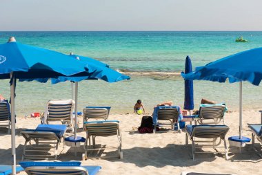 Turist beach umbrel altında bir kumlu plajda şezlong üzerinde rahatlatıcı