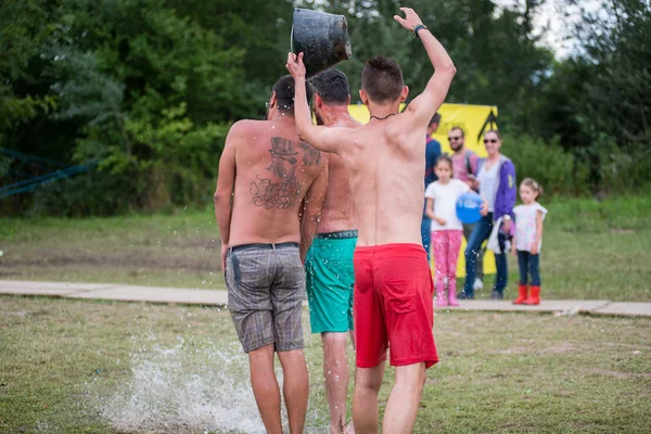 彼の友人の頭にバケツから水の男 spours — ストック写真