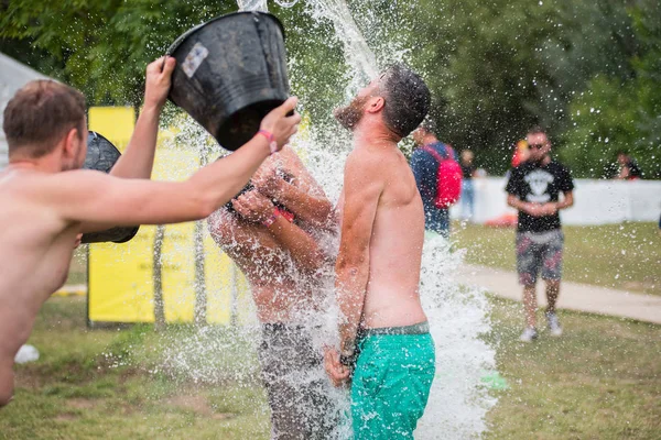 Guy spours water from a bucket on his friend head — Stock Photo, Image