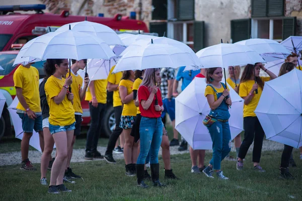 Young people playing a game with white umbrellas — Stock Photo, Image