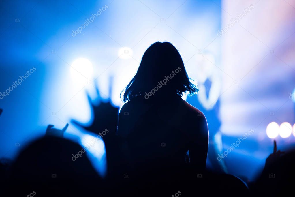 Silhouette of concert crowd in front of bright stage lights