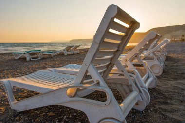 Gün batımında kumsal beyaz şezlong
