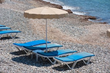 kumsalda güneşlik ve şemsiyeler