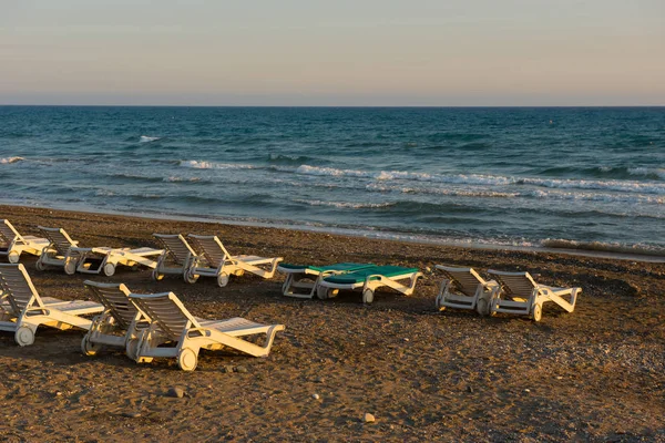 Weiße Sonnenliegen an einem Sandstrand bei Sonnenuntergang — Stockfoto