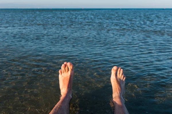 Deniz çamaşır adamın ayakları dalgalar.