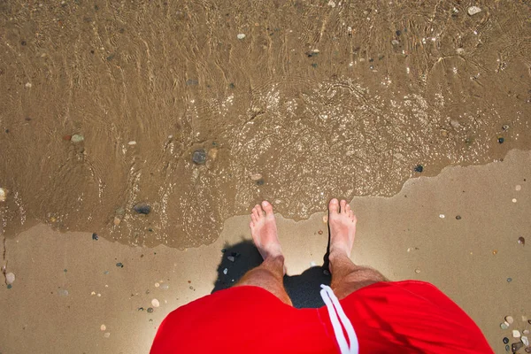 Los pies del hombre en la arena. Olas marinas acercándose playa —  Fotos de Stock
