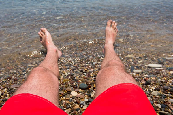 Sea waves washing man\'s feet