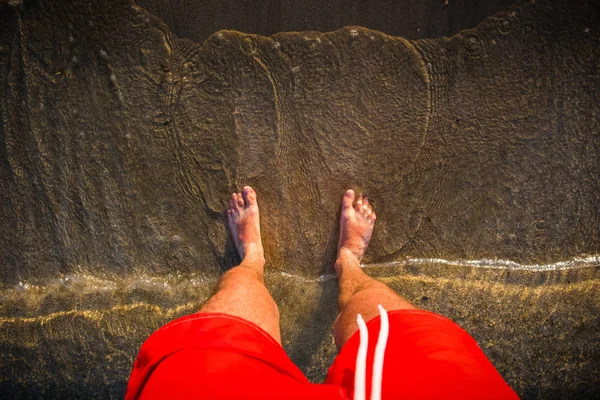 Pánské nohy v písku, vlny se blíží beach — Stock fotografie