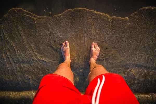 Les pieds de l'homme dans le sable de la plage, vagues de mer — Photo