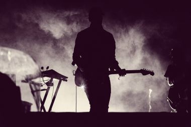 Guitarist playing live in stage lights clipart