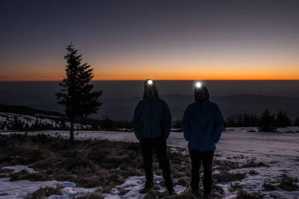 Путешественники с фарами на зимнем рассвете в горах — стоковое фото