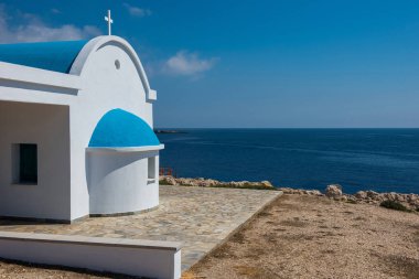 Sahilde mavi çatılı geleneksel Beyaz Şapel. Agioi 