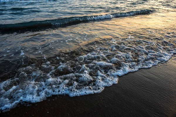 Ondas que se aproximam da praia de areia durante o pôr do sol — Fotografia de Stock