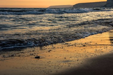 Günbatımı sırasında kumsala yaklaşırken dalgalar