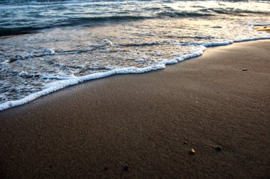 Günbatımı sırasında kumsala yaklaşırken dalgalar