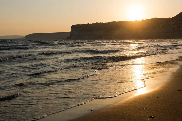 Hullámok közeledik homokos strand, a naplemente alatt — Stock Fotó