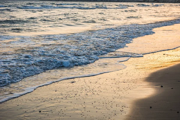 Vlny se blíží písečná pláž při západu slunce — Stock fotografie