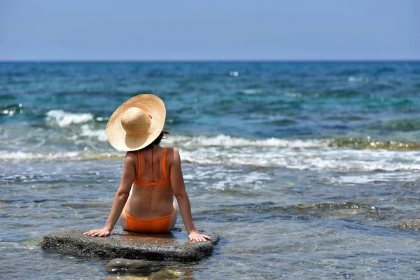 Seksi bikini bronzlaşma kadın rahatlatıcı bir şapka ile sahilde — Stok fotoğraf